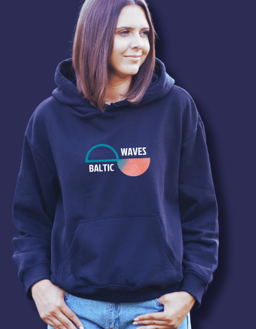Ein Frau schaut freundlich in die Kamera. Sie trägt einen blauen Kapuzensweater mit dem Baltic Waves Logo.
